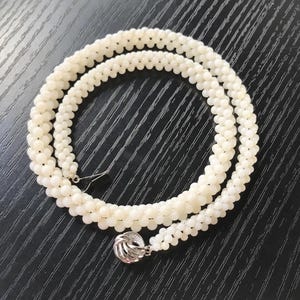 May include: A white pearl necklace with a silver clasp. The necklace is made of small, round pearls and is approximately 18 inches long.
