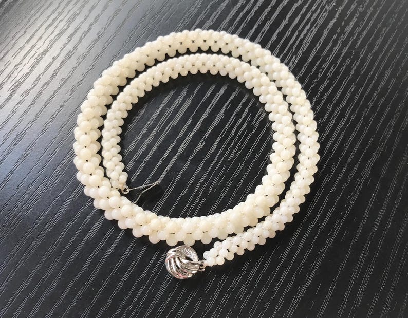 May include: A white pearl necklace with a silver clasp. The necklace is made of small, round pearls and is approximately 18 inches long.