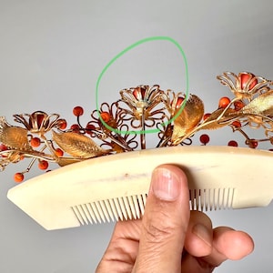 Op de afbeelding: Gouden haar kam met koraal gekleurde bloemen en bladeren. De kam is versierd met kleine rode kralen.