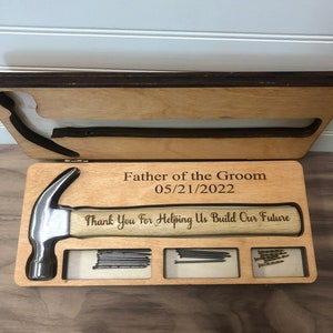 May include: Wooden box with a hammer and nails inside. The box is engraved with the text "Father of the Groom 05/21/2022 Thank You For Helping Us Build Our Future".