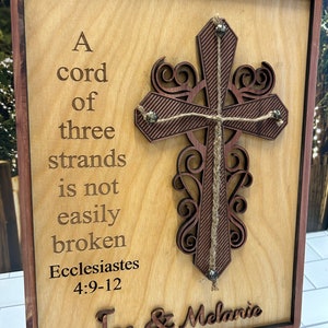 May include: A wooden sign with a brown cross and the text "A cord of three strands is not easily broken Ecclesiastes 4:9-12" and "Joe & Melanie".