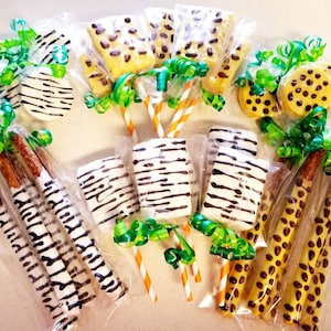 May include: Assortment of animal print themed treats, including pretzel rods, marshmallow pops, and cookies. The treats are wrapped in clear plastic bags and tied with green ribbon.