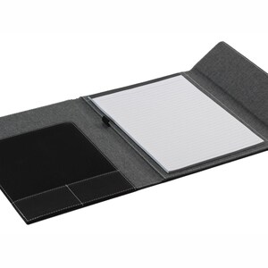 May include: A black and gray folder with a notepad and a pocket on the inside. The folder has a textured fabric exterior and a smooth leather interior.