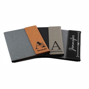 May include: Three personalized leatherette folders with different names and designs. The first folder is brown with the name "Amanda" and a floral design. The second folder is gray with the name "Anderson" and a simple letter "A". The third folder is black with the name "Jennifer" in cursive.