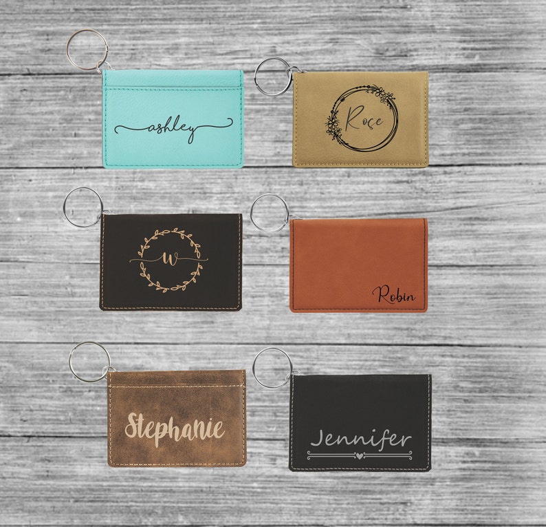 May include: Six personalized leather keychains with different names and designs. The keychains are brown, black, tan, and blue. The names on the keychains are Ashley, Rose, Robin, Stephanie, and Jennifer.