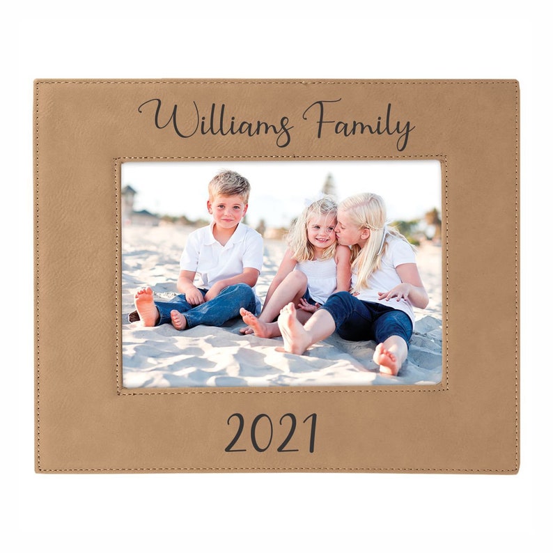 May include: A tan leather photo frame with a stitched border. The frame has a photo of three children on a beach. The text "Williams Family" is printed at the top of the frame and "2021" is printed at the bottom.