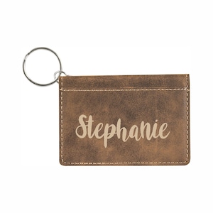 May include: A brown leather key chain with a silver key ring and the name "Stephanie" embossed in a cream color.