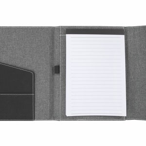 May include: A gray fabric folder with a black leather pocket and a lined notepad inside.