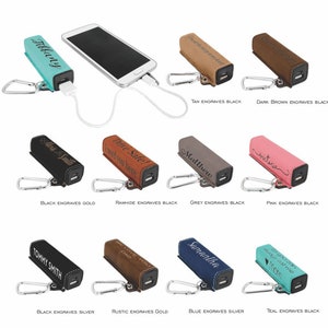 May include: An assortment of personalised phone charger cases in various colours and engravings. The cases are made of leather and have a keychain attached. The engravings include names, messages and designs.