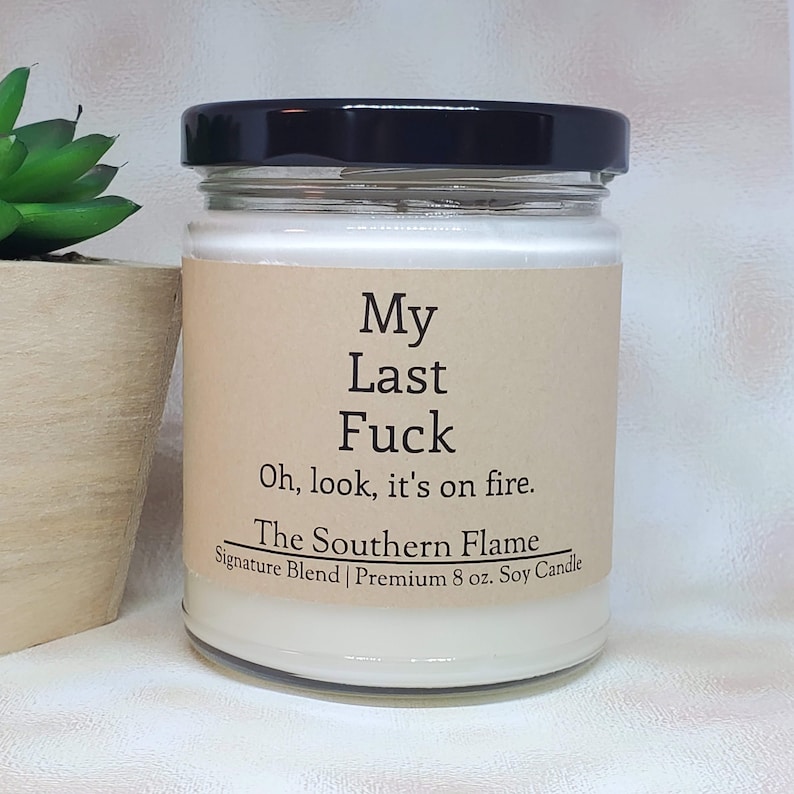 May include: A glass jar candle with a black lid. The label reads "My Last Fuck, Oh, look, it's on fire." and "The Southern Flame Signature Blend Premium 8 oz. Soy Candle."