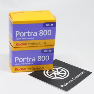 Peut inclure: Deux boîtes de pellicule négative couleur Kodak Professional Portra 800. Les boîtes sont violettes avec des dessus jaunes et présentent le texte "Portra 800" et "Kodak Professional". Une carte noire et blanche avec le texte "Pattern Cameras" est également présente.