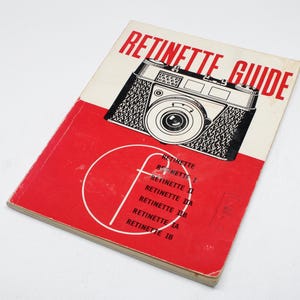 May include: A vintage "Retinette Guide" book. The cover features a black and white illustration of a camera with the title in red. The book is red and white with text that reads "Retinette I, II, IIA, IIB, IA, IB".