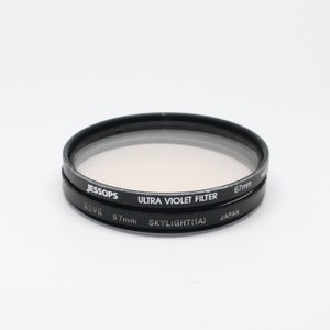 May include: Two black camera lens filters, one labeled "HOYA 67mm SKYLIGHT(1A) JAPAN" and the other labeled "JESSOPS ULTRA VIOLET FILTER 67mm".