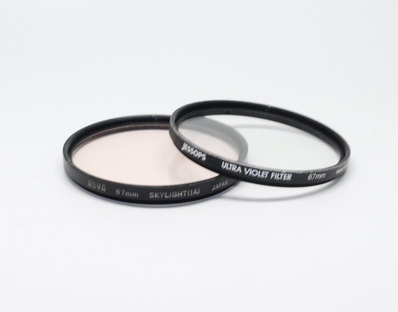 May include: Two 67mm camera lens filters. One is a clear ultra violet filter by Jessops, the other is a pink skylight filter by Hoya.