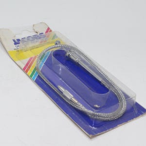 Puede incluir: Un cable flexible plateado con conectores en cada extremo, empaquetado en un blíster transparente. El embalaje tiene una base azul con una franja de arcoíris y la palabra "DIS" visible.