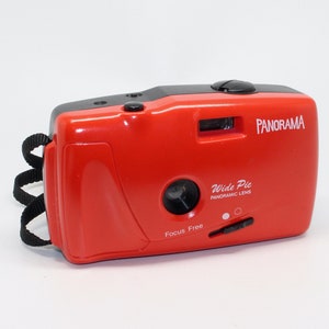 May include: A red and black 35mm film camera with a black strap. The camera has a focus free lens and a wide pic panoramic lens. The camera says "Panorama" on the top and "Wide Pic Panoramic Lens" on the front.