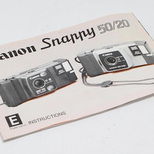 Peut inclure: Un manuel d'instructions en noir et blanc pour un appareil photo Canon Snappy 50/20. Le manuel présente des images de l'appareil photo et du texte en anglais.