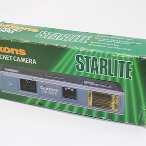 May include: A rectangular green cardboard box for a Dixons Starlite 110 pocket camera. The box features the product name in white and orange text, a graphic of the grey camera with a yellow flash, and lists features like built-in electronic flash.
