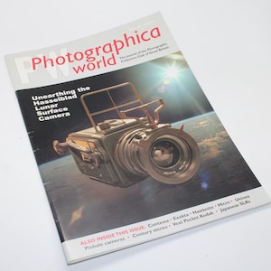 以下が含まれることがあります： 「Photographica world」というタイトルの雑誌で、表紙にはHasselblad Lunar Surface Cameraが掲載されています。雑誌の表紙には「Unearthing the Hasselblad Lunar Surface Camera」と書かれています。雑誌には他のカメラブランドも掲載されています。
