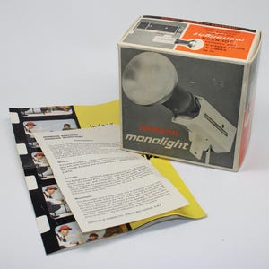 May include: Vintage Johnson Monolight flash unit in its original box. The box features a graphic of the flash unit and the text "Johnson Monolight". Includes instruction sheets and a film strip. The box is red, white, and black.