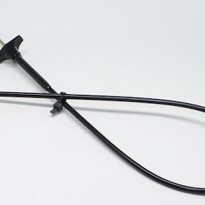 Puede incluir: Una herramienta de cable flexible negra con un mango y un gancho en el extremo. La herramienta está diseñada para recuperar objetos de lugares de difícil acceso.