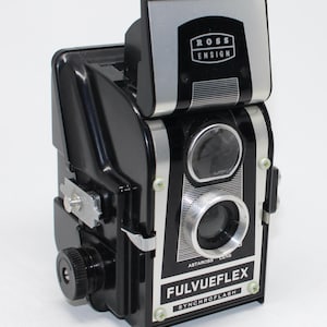 May include: A black and silver Fulvueflex camera with the Ross Ensign logo. The camera has a silver viewfinder and lens details. The text "FULVUEFLEX SYNCHROFLASH" is visible on the front.