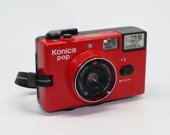 Cámara compacta roja Konica Pop de 35 mm con estuche y manual. Muy buen estado y probada c.1982.