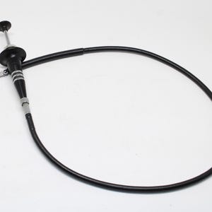 May include: A black camera shutter release cable with a flexible cord and a metal plunger mechanism. The device features a silver-toned locking ring and a threaded tip, designed for remote operation of a camera shutter via a mechanical connection.