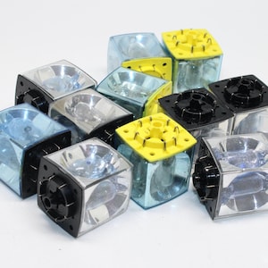 May include: A collection of clear, square-shaped light fixtures with black, silver, and yellow accents. The fixtures have a transparent, blue-tinted front and a reflective interior, suggesting they are designed for illumination.