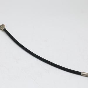 May include: A black camera shutter release cable with a silver-colored tip and button. The cable is flexible and covered in a woven material. The button is round and has a small, flat surface.