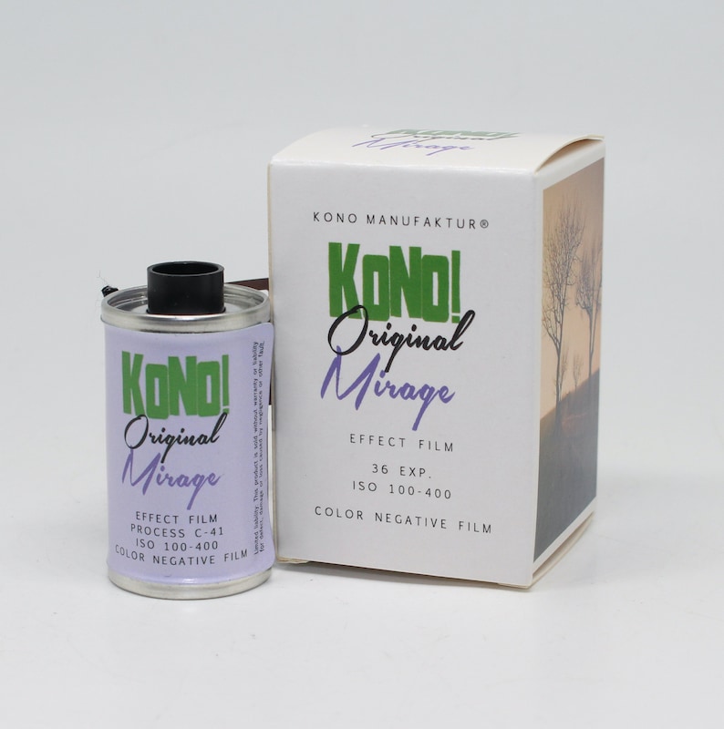 May include: A silver film canister with a green and white label that reads "KONO! Original Mirage Effect Film Process C-41 ISO 100-400 Colour Negative Film". The canister is next to a white box with the same label and the text "KONO MANUFAKTUR&reg;" at the top.
