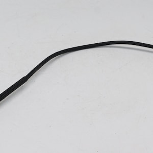 Pode incluir: Um disparador de cabo de câmera vintage com um tubo preto flexível e um mecanismo de bloqueio e êmbolo de metal prateado. Este acessório permite disparar o obturador de uma câmera remotamente.