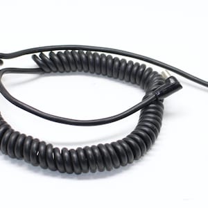 May include: A black coiled cable with a straight section and a connector at the end. The coiled portion is circular and the cable is on a white background.