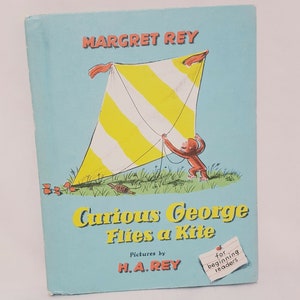 Könnte beinhalten: Ein Vintage-Kinderbuchcover mit einem gelben und weißen gestreiften Drachen, der von einem Affen geflogen wird. Der Buchtitel lautet "Curious George Flies a Kite" von Margret Rey mit Illustrationen von H.A. Rey. Das Cover enthält auch den Text "Für Leseanfänger".
