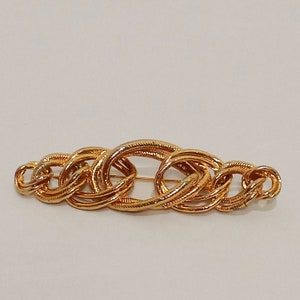 以下が含まれることがあります： チェーンのデザインの金色のブローチ。ブローチは複数の連鎖する円からできています。