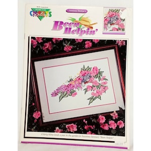 May include: Cross stitch pattern featuring a cat sleeping in a pink flower bush. The pattern is titled "Been Helpin'" and is by Suzanna Denton.
