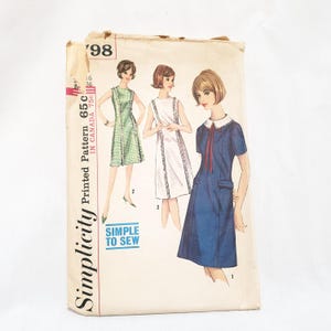 May include: Vintage Simplicity sewing pattern for a dress. The pattern is for a sleeveless dress with a Peter Pan collar and a bow. The pattern is printed on a white background with a blue border. The pattern number is 65C. The text "Simple to Sew" is printed on the pattern.