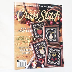 Puede incluir: Una portada de revista de "For the Love of Cross Stitch" presenta diseños de frutas bordadas a punto de cruz enmarcadas: manzana, pera, melocotón y cerezas. La portada incluye el texto: "23 Fabulous Fall Projects!" y "Pick Our Fancy Fruits". La revista es de septiembre de 2000.