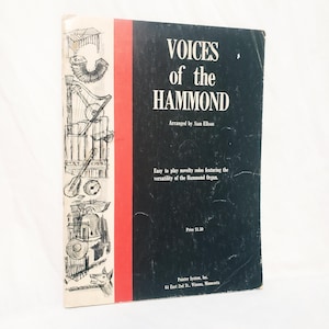 Op de afbeelding: Vintage muziekboek getiteld "VOICES of the HAMMOND" met een zwarte kaft en rode rug. De kaft bevat illustraties van muziekinstrumenten en de tekst "Arranged by Sam Ellson". Het boek bevat originele solo's voor het Hammond-orgel.