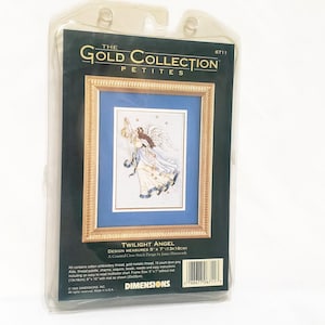 Puede incluir: Un kit de punto de cruz titulado "Twilight Angel" de The Gold Collection Petites. El kit incluye una imagen enmarcada de un ángel con marco dorado, paspartú azul y vestido blanco y dorado. El diseño mide 13cm x 18cm.