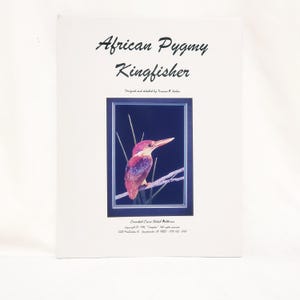 May include: A print with an image of an African Pygmy Kingfisher bird on a branch, framed within a dark blue border. The bird is depicted with reddish-brown and purple feathers. The text "African Pygmy Kingfisher" is displayed at the top.