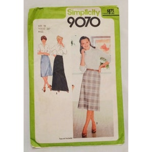 May include: Simplicity sewing pattern number 9070 for a skirt. The pattern shows three different skirt styles: a knee-length skirt with a plaid pattern, a midi-length skirt with a solid black fabric, and a shorter skirt with a solid blue fabric. The pattern is for size 10 with a 25 inch waist.