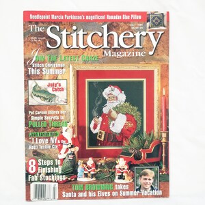 May include: The Stitchery Magazine, July 1996, features a Santa Claus needlepoint design. The cover includes text about Christmas stitching, pulled thread techniques, and finishing stockings. The magazine has a brown and red color scheme.