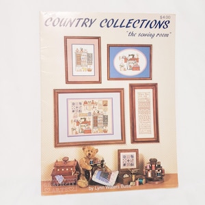 May include: A Country Collections craft book cover featuring framed cross-stitch samplers and a teddy bear with a sewing machine. The text reads "COUNTRY COLLECTIONS" and "the sewing room". The cover has a light beige background with a dotted pattern.