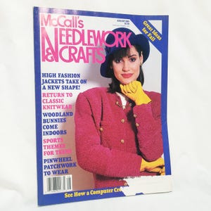 Könnte beinhalten: Ein Magazin-Cover für McCall's Needlework & Crafts, Ausgabe August 1987. Das Cover zeigt eine Frau, die eine rosafarbene Strickjacke, einen blauen Hut und gelbe Handschuhe trägt. Der Text auf dem Cover lautet "High Fashion Jackets Take On A New Shape!" und "Great Ideas for Fall".