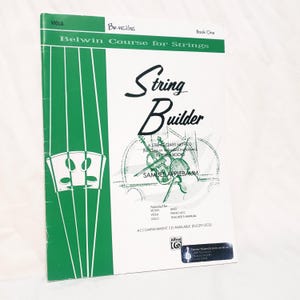 May include: A white and green music instruction book titled String Builder Book One for viola by Samuel Applebaum. The cover features a green vertical stripe with a bridge illustration, a central graphic of string instruments, and text.