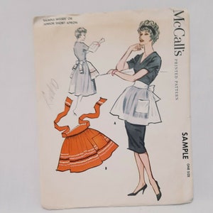 Könnte beinhalten: Vintage McCall's Nähmuster für eine kurze Schürze für Jugendliche. Das Muster ist für ein einheitsgrößen Muster und enthält Anweisungen zum Nähen einer kurzen Schürze mit einer Tasche und einer Schleife.