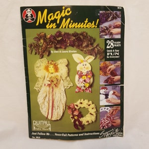 May include: A book titled "Magic in Minutes!" with a cover featuring a variety of fabric crafts, including a lace angel, a bunny, a wreath, and a snowman. The book is by Jean & Laura Klevlan and includes 28 no-sew projects.