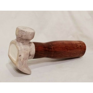 May include: A ceramic hammer with a white head and a brown wooden handle.