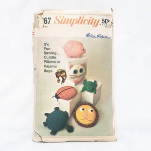 May include: Vintage Simplicity sewing pattern number 67 for making cuddle pillows or pajama bags. The pattern features illustrations of a pig, cat, ladybug, frog, turtle, and lion.
